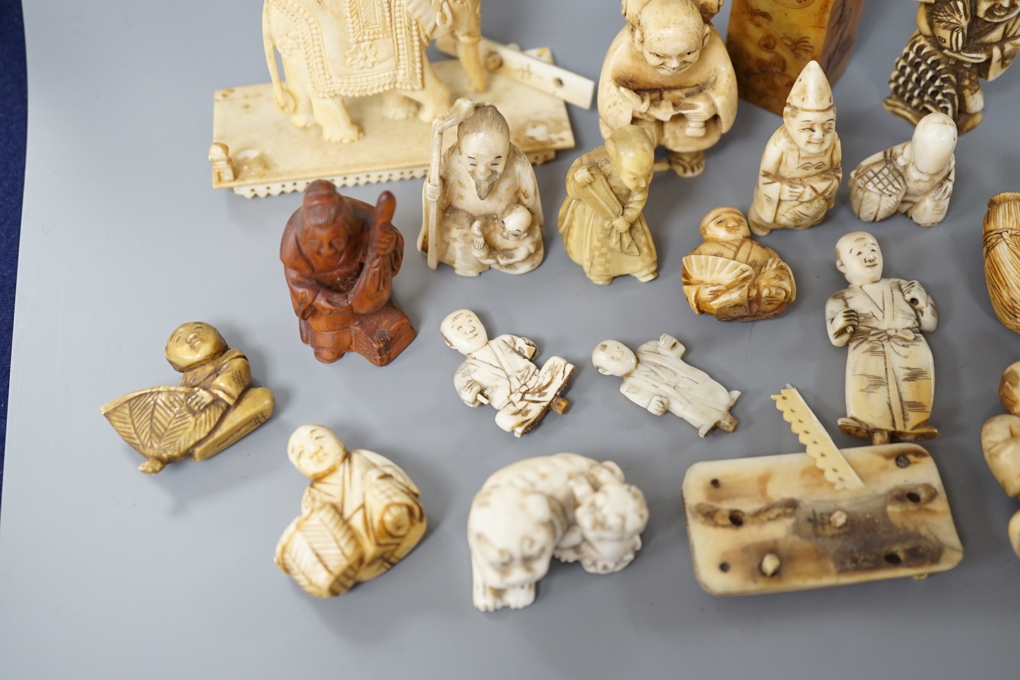 A collection of various ivory carvings including netsuke, a soapstone seal and carved wood netsuke